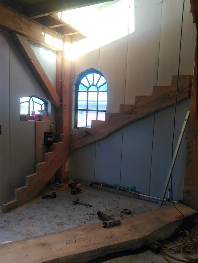Houten trapboom en gebogen glas in loodraam in een verbouwing